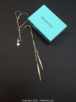 Full view of necklace draped next to Tiffany & Co box on black background