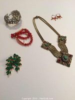 Six vintage statement jewelry pieces arranged in a photo including three bracelets, two pairs of earrings, and one necklace with rhinestones, crystal, and jade-like stones.