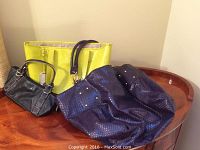Photo showing all three handbags: yellow Ralph Lauren tote, black Kenneth Cole bag, and large blue Big Buddha handbag.