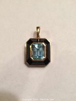 Front view of pendant showing black onyx border and emerald-cut blue topaz