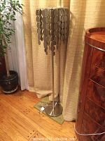 Full view of the floor lamp showing the metal base, slender metal stand, and wooden disc pendant shade in chandelier style.