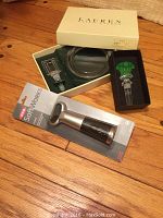 Ralph Lauren bottle stopper and coaster in open box, Versace stopper in black box, OXO cork pull in packaging laid on wooden floor