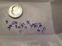Photo showing 26 small square cut loose Tanzanite stones alongside a US dime for scale.
