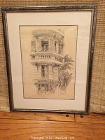 Full view of framed pencil drawing leaning against wicker backdrop on hardwood floor