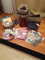 Full lot of crafting supplies laid out on floor including scrapbooks, alphabet stickers, floral hat box, pinecones, and lampshades.