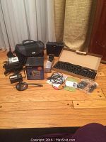 Overview of lot items including boxed Dell keyboard and mouse, Garmin Nuvi 680 box, Nikon camera bag, cabling, and other accessories.