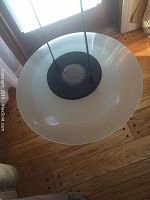 Top view of the frosted glass lamp shade suspended by black cords from the ceiling plate.