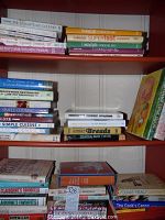 Shelves with assorted cookbooks including The Enlightened Gourmet and From Julia Child's Kitchen, stacked and upright, showing over 25 books total.