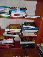Shelves of stacked cookbooks including various culinary topics and authors
