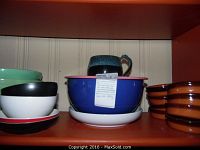 Lot display shelf showing Bauer mixing bowls (light green), Spanish Cazuelas (brown), hand-thrown pottery mug on top of Fiesta plate.