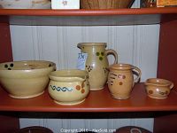Full grouping of six handmade ceramic vintage German pottery pieces on shelf, showing bowls, pitchers, and creamers with colorful dot and stripe decorations.