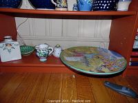 Shelf with various pieces of Italian pottery including large serving plate with farmer scene and smaller ceramic items such as pots and bowls.