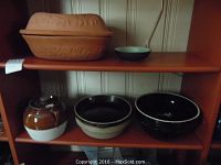 Terra cotta Romertopf roaster and small dish on top shelf; vintage bean pot, antique bread bowl, and casserole pot on lower shelf