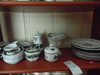 Shelf view showing Meissen Grapeleaf coffee pot, creamer, sugar bowl, cups, saucers, petit-fours stand and stack of Gien plates