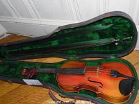 Violin and open hard shell case with green velvet interior