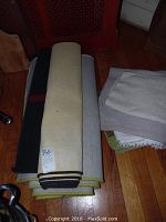 Rolled rugs stacked showing the varied woven rugs including black and cream striped and solid colors.