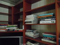 Wide image of several bookshelves packed with over 40 cookbooks of assorted types including vegetarian, French, Asian, and desserts.
