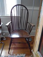 Front view of the vintage Windsor chair showing dark wood finish, curved back with several spindles and armrests.