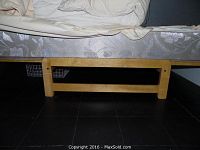 Side view of the light wood futon frame showing square leg and horizontal support rails.