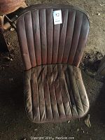Front view of one red vinyl bucket seat showing pleated seat cushion and backrest with sticker '12'