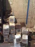 Stack of cardboard boxes containing alternators branded Crompton Greaves and others, showing labels and wear from storage.