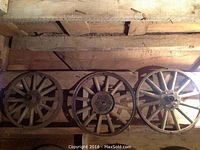 Three wooden spoke wheels laid side by side on a wooden surface, showing overall condition.