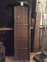 Full view of the wooden toboggan showing top to bottom with slats and metal runners on sides.