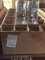 Box of clear NFL promotional glasses with team logos of Dallas Cowboys and Seattle Seahawks visible in cardboard organizer.