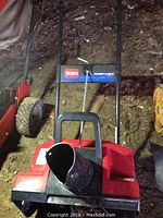 Front view of red Toro snow blower with black snow chute and control handlebar panel