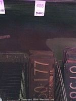Photo of wire baskets with stacked vintage Massachusetts license plates inside, numbers clearly visible on front plate, showing plate number 150-177.