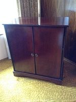 Front view of the wood TV cabinet showing two doors with metal pull handles and minor wear on wood finish.