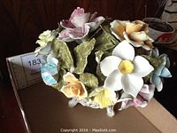 Front view of Capodimonte porcelain basket with multicolored flowers and leaves, showing detailed craftsmanship and some missing flowers.