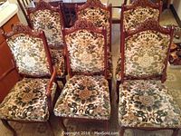 Six dining chairs arranged together showing matching carved frames and upholstery.