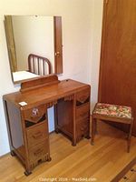 Wooden desk with drawers and attached rectangular mirror, showing overall vintage condition and warm wood tones.
