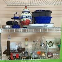 Shelf displaying Biscotti jar, salt and pepper shakers, silicone and other bakeware, glass bottles, candles, and various kitchenware items.