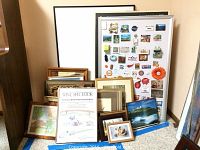 Large assortment of framed paintings and prints, some leaning, with one large magnetic board in background