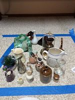 Photo of all small vases, pitchers, and Kosta glass sculpture grouped on floor, including Staffordshire Pig and Whistle, various ceramics, and glass pieces.