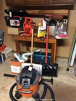 Ridgid shop vacuum with hose in front of table with various tools and supplies