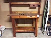 Front view of the wooden potters bench showing center opening with removable slats, drawer above, and bottom shelf.