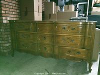 Front view of the vintage wooden dresser showing nine drawers and carved detailing on drawer fronts.