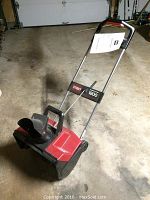 Full view of Toro Power Curve 1800 electric snowthrower showing red and black housing, discharge chute, and metal handle.