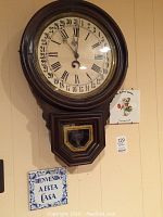 Front view of large wooden calendar wall clock mounted on wall