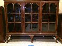 Full front view of wooden cabinet showing three glass-pane doors and cabriole legs