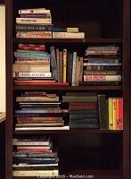 Four shelves filled with assorted books including language, cookbooks, and literary works