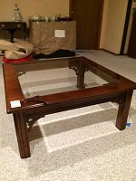 Square wooden coffee table with glass top showing overall table and legs.