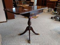 Full view of the wooden side table with drop leaves extended, showing polished surface and drawer.