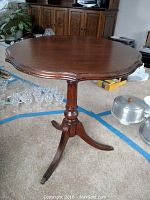 Front angle view of the vintage wooden slant top side table showing scalloped top and pedestal base with three legs.