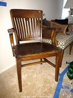 Front view showing the wooden desk chair with slatted backrest, armrests, and solid wood seat.