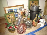 Photo shows commercial grade stock pot, vintage juicer, stained glass bottles, Stangl Granada Gold planter with beaded flowers, assorted jello molds, framed seashell wall art, meat grinder, and other assorted kitchenware pieces arranged on the floor.