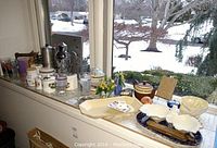 Wide view of the window ledge lined with various collectible ceramics and glassware including candy dishes, teapot, canisters and glasses